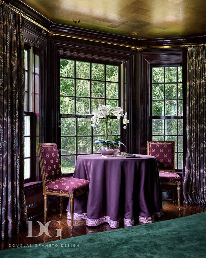 View of a bay window in a purple dining room. There is a small purple cloth covered table and two chairs. Zimmer & Rohde’s curtains