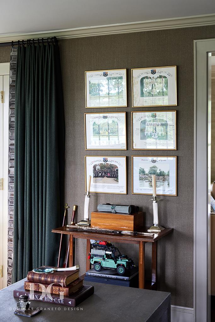 A view of a wall next to a window in the office featuring old school photos, with a lego model jeep underneath.