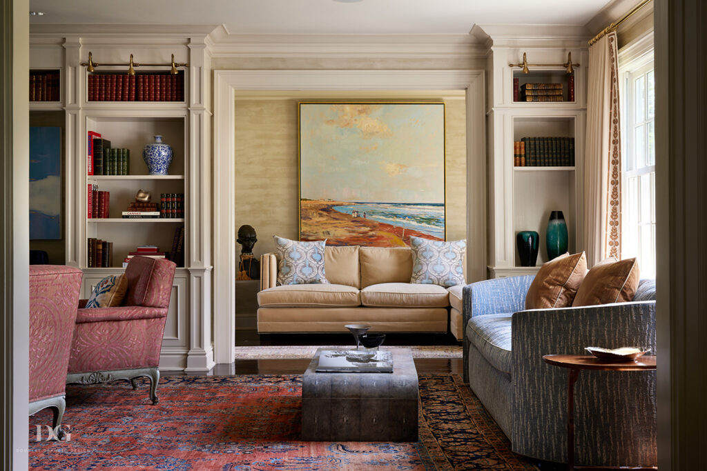 A living room with upholstered sofas, antique rugs, built-in bookcases, and Holland & Sherry curtains