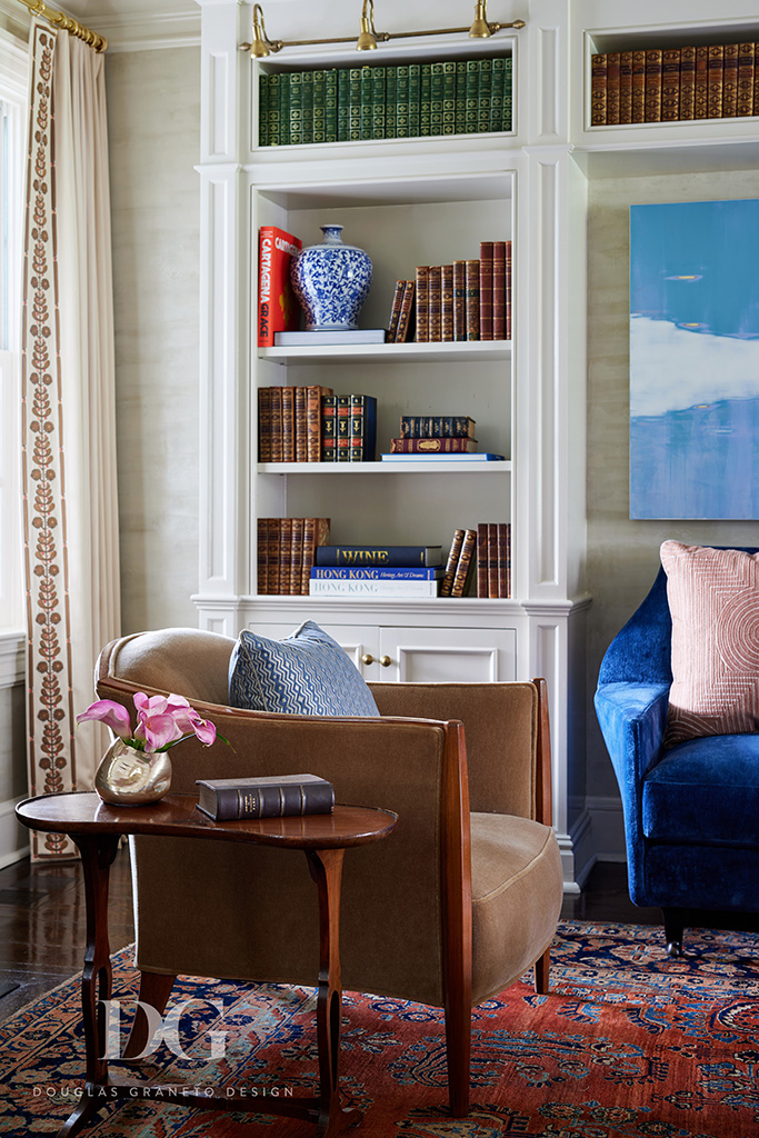Detail of a vintage art deco chair next to a buitl-in bookcase and Holland & Sherry curtains