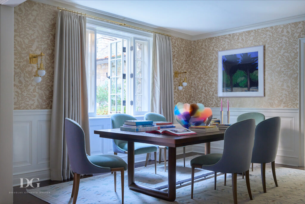 Half paneled dining room with John Rosselli wallpaper and dining table and blue upholstered modern chairs. Doris Leslie Blau carpet