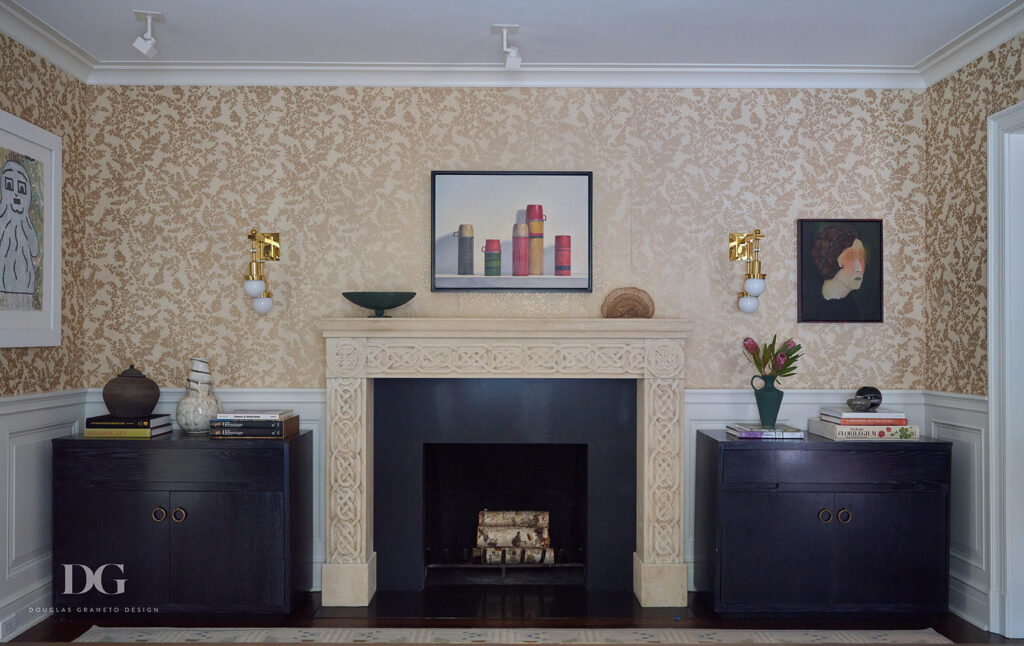 A dining room fireplace with matching dark wood buffets either side. John Rosselli wallpaper with white panelling below