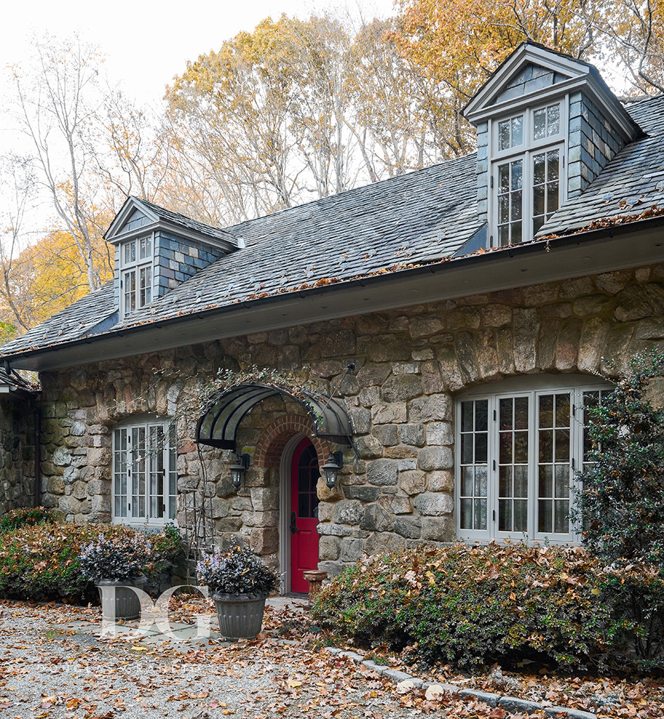Stone cottage with red door and dormer windows