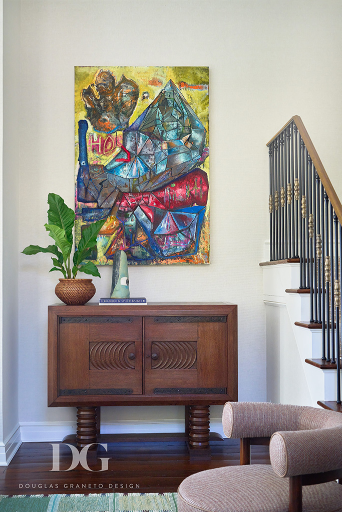 Detail of a corner of a living room with a wood console table and art hanging above