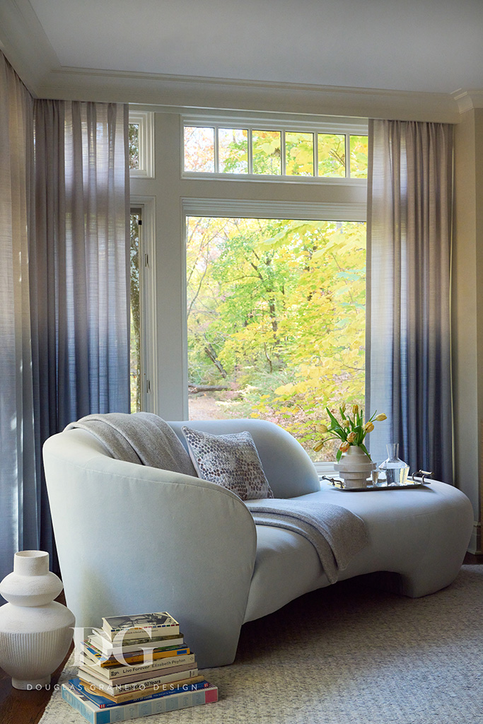 White curved bedroom chaise, Doris Leslie Blau rug, blue curtains, in a corner of a bedroom